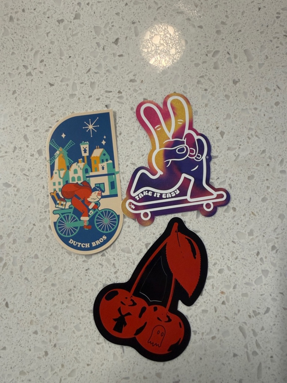 Dutch Bros multicolor peace skate, blue village bike, and red cherry stickers